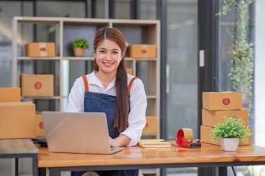 Küçük işletme girişimcisi KME, kutuda kumaş paketleyen Asyalı kadın. Portre genç Asyalı küçük işletme sahibi ev sahibi, çevrimiçi satış pazarlama teslimatı, KME e-ticaret tele pazarlama kavramı.