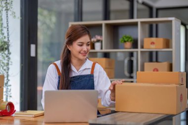 Startup small business entrepreneur SME, asian woman packing cloth in box. Portrait young Asian small business owner home office, online sell marketing delivery, SME e-commerce telemarketing concept.
