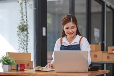 Küçük işletme girişimcisi KME, kutuda kumaş paketleyen Asyalı kadın. Portre genç Asyalı küçük işletme sahibi ev sahibi, çevrimiçi satış pazarlama teslimatı, KME e-ticaret tele pazarlama kavramı.