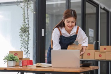 Küçük işletme girişimcisi KME, kutuda kumaş paketleyen Asyalı kadın. Portre genç Asyalı küçük işletme sahibi ev sahibi, çevrimiçi satış pazarlama teslimatı, KME e-ticaret tele pazarlama kavramı.