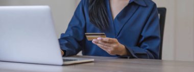 Akıllı telefon ve kredi kartını elinde tutan çekici Asyalı kadın, mobil bankacılık uygulaması veya çevrimiçi alışveriş uygulaması kullanıyor...