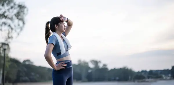 Asian woman is exhausted and wipes away sweat after running, jogging, exercising or exercising in the morning. sports for health Tired and out of breath Freshness and sweating.