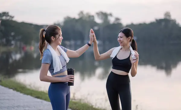 High five successful and fit friends with goals, motivation and a winning attitude in celebration of goals, sports, teamwork. And happy women celebrate jogging. exercise and cardio progression.