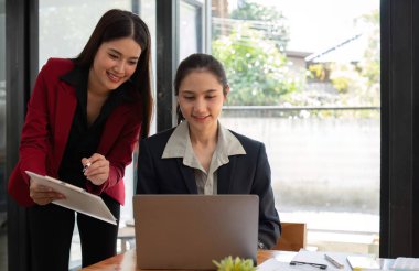 Ofis konferans odasında proje stratejisini tartışan iki iş kadını, modern işyerindeki iş arkadaşlarıyla proje planlamasını tartışıyor, mali veri raporu hakkında tavsiyelerde bulunuyor.