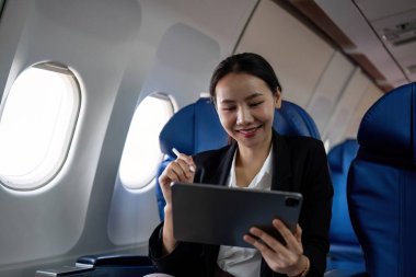 Genç Asyalı yöneticiler birinci sınıf. Dijital tabletler, dizüstü bilgisayarlar ve akıllı telefonlar ile birden fazla iş. Stil olarak seyahat et..