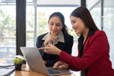 Ofis konferans odasında proje stratejisini tartışan iki iş kadını, modern işyerindeki iş arkadaşlarıyla proje planlamasını tartışıyor, mali veri raporu hakkında tavsiyelerde bulunuyor.