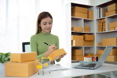 Business From Home Asian woman preparing package delivery box Shipping for shopping online. young start up small business owner at home online order.