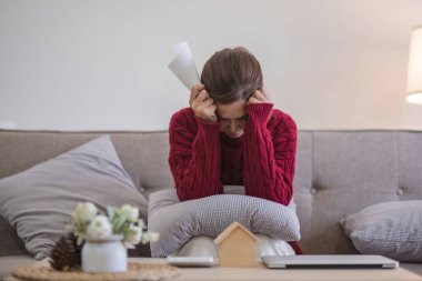 Kadın, faturaları gözden geçirirken stresli hissediyor. Mali stres, tatil sezonu ve ev finansmanı kavramı.