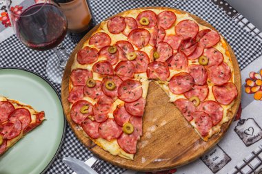 Lezzetli pepperoni pizza tahtada, masa örtüsünün üstünde.