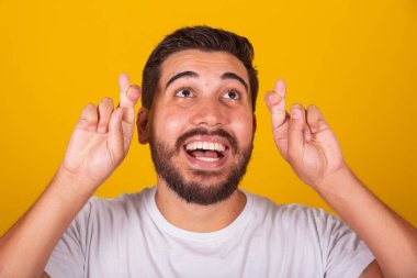 Brezilyalı Latin Amerikalı adam, şans, dilek, umut, tezahürat, piyango, sarı arka plan.