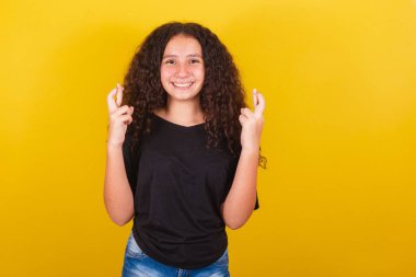 Brezilya 'lı, Latin Amerikalı afro saç, sarı arka plan, gülümseme, şans işareti, şans dileme, bükme, dileme, mutlu olma.