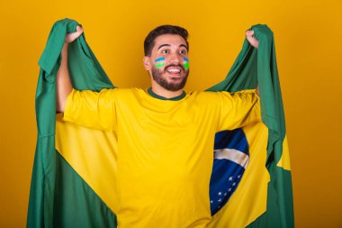 Brezilyalı adam, Latin Amerikalı, Brezilya için tezahürat yapıyor, 2022 Dünya Kupası 'nda, vatansever, milliyetçi, titreşimli Brezilya bayrağı, tezahürat ve zıplama, mutluluğun, sevincin ve kutlamanın sembolü, Brezilya bayrağıyla
