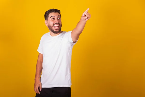 ブラジル系ラテン系アメリカ人の男性は 手を指差して 何かを見たと言います 驚きのコンセプトとポインティングコンセプト 黄色の背景 — ストック写真