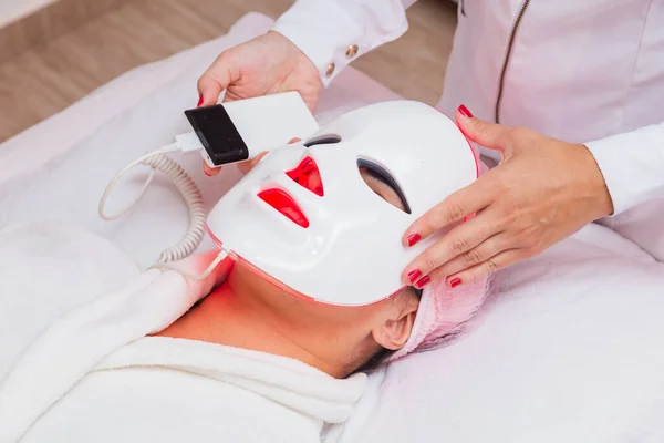 Use of led mask on patient for aesthetic treatment, relaxation, rejuvenation, color therapy, light therapy, skin care. close on procedure