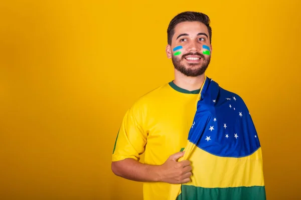 Brazilian man, latin american, cheering for brazil, in the world cup 2022, looking at camera, smiling, imposing, patriot, nationalist, fan.