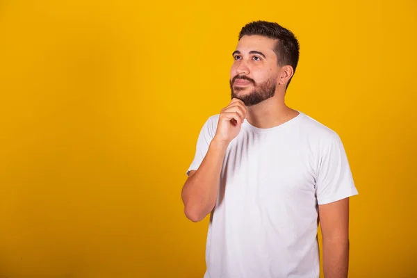 ブラジル系ラテン系アメリカ人の男性の額とあごの思考を表す手 集中的 不確実性 黄色の背景 — ストック写真