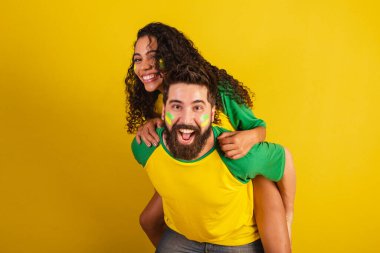 İki Brezilyalı futbol taraftarı, ulusun renginde giyinmiş, siyah kadın, beyaz erkek. Öpücük, aşk.
