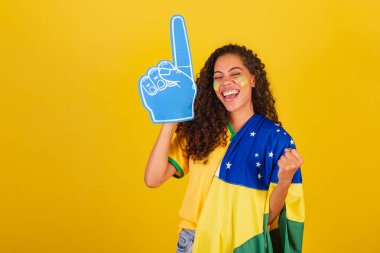 Genç siyah Brezilyalı kadın, futbol fanatiği. Bayrak ve aksesuarlarla, kutlama hedefi.
