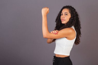 Genç siyah Brezilyalı kadın, kaldırılmış ve kapalı yumruklu, militanlık, feminizm.