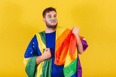 Brezilyalı beyaz adam, Brezilyalı futbol taraftarı, elinde LGBT bayrağı, cinsiyet eşitliği konsepti, Igbt gururu, kendinden emin. çeşitlilik. Cinsellik.