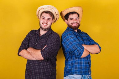 Festa Junina için tipik kıyafetler giyen iki arkadaş. Kollarını kavuşturup gülümseyerek.