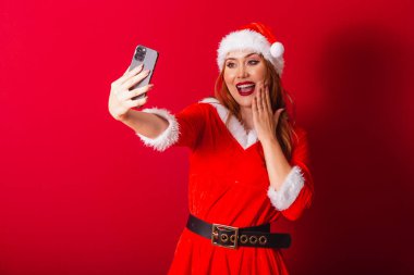 Güzel Brezilyalı kızıl saçlı kadın, Noel kıyafetleri giymiş, Noel Baba. akıllı telefondan video çağrısı.