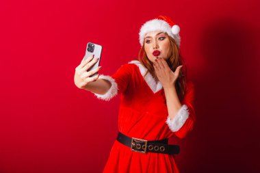 Güzel Brezilyalı kızıl saçlı kadın, Noel kıyafetleri giymiş, Noel Baba. akıllı telefondan video çağrısı.