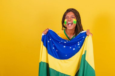 siyah kadın genç Brezilyalı futbol fanatiği. Brezilya bayrağı taşıyor, el sallıyor ve kutluyor..