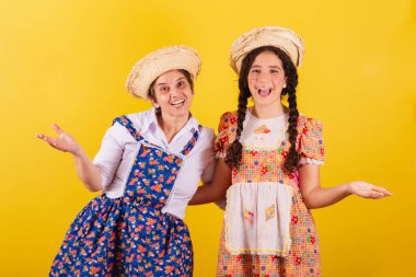 Büyükanne ve torun tipik Festa Junina kıyafetleri giymişler. Hoş geldiniz, hoş geldiniz, davetkâr. gülümsüyor.