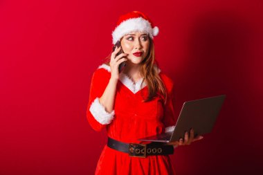 Güzel Brezilyalı kızıl saçlı kadın, Noel kıyafetleri giymiş, Noel Baba. Not defteri ve akıllı telefon tutuluyor, meşgul.