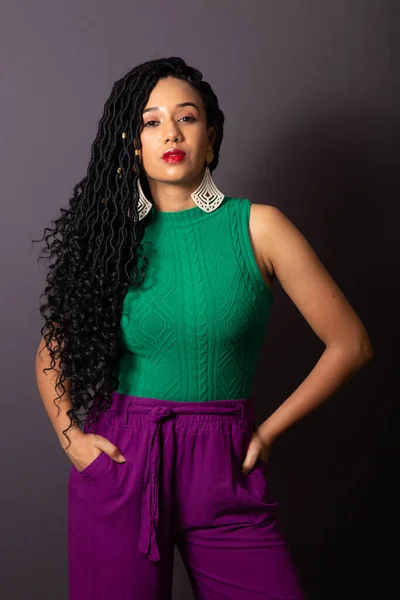 stock image Beautiful Brazilian black woman, dressed in green and purple. Half body portrait, gray infinity background.