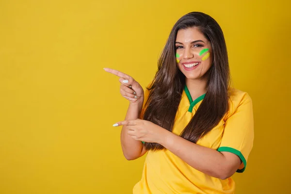stock image Woman supporter of Brazil, world cup 2022, soccer championship, presenting product with fingers to the left.