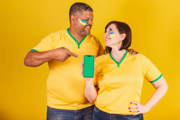 カップル 赤髪の女性と黒の男 ブラジルのサッカーファン スマートフォン オンラインモバイル — ストック写真