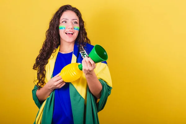 Woman soccer fan, fan of brazil, world cup, holding horn, sound instrument, making noise when cheering.