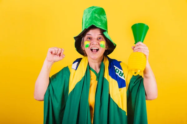 大人の女性ブラジルのサッカーファン旗と帽子をかぶってホーン ノイズを使って応援します — ストック写真