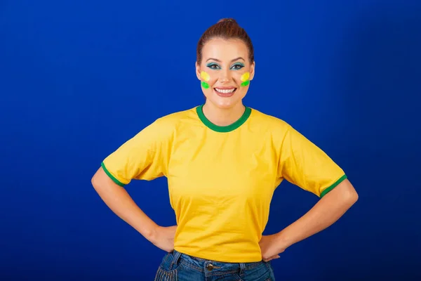 白人妇女 红头发 巴西球迷 巴西人 蓝色背景 手放在腰部 — 图库照片