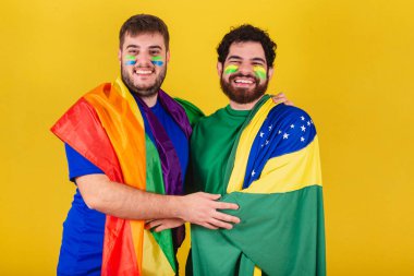 Brezilya 'lı bir çift erkek, futbol taraftarı, LGBT bayrağı takıyor.