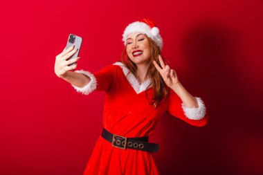 Güzel Brezilyalı kızıl saçlı kadın, Noel kıyafetleri giymiş, Noel Baba. akıllı telefondan video çağrısı.