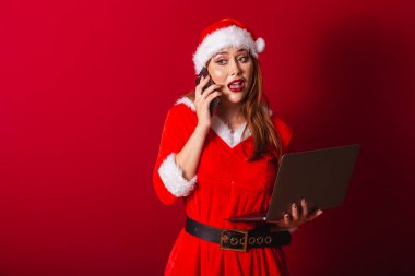 Güzel Brezilyalı kızıl saçlı kadın, Noel kıyafetleri giymiş, Noel Baba. Not defteri ve akıllı telefon tutuluyor, meşgul.