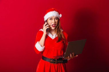 Güzel Brezilyalı kızıl saçlı kadın, Noel kıyafetleri giymiş, Noel Baba. Not defteri ve akıllı telefon tutuluyor, meşgul.
