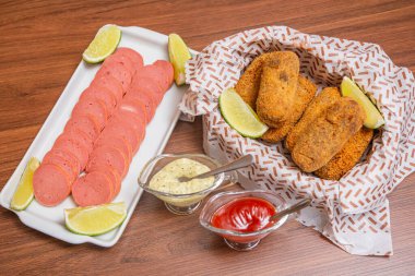 Tavuk kroket ve Cambu sosisi, limon dilimleri, acı biber sosu ve mayonez ile servis edilen tipik Brezilya aperatifi. Tahta masada.