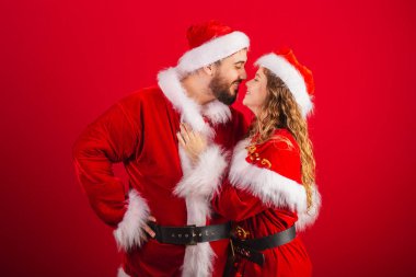 Brezilyalı çift, Noel kıyafetleri içinde, Noel Baba, sarılıyorlar, öpüşüyorlar.