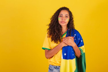 Genç siyah Brezilyalı kadın, futbol fanatiği. Brezilya bayrağıyla. Milli marşı söylüyor..