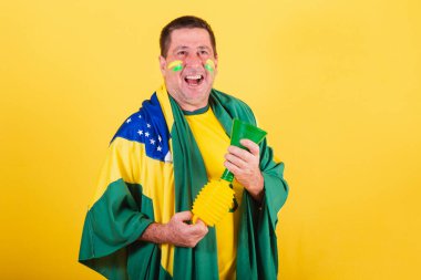 Yetişkin bir adam, Brezilya 'dan futbol fanatiği, bayrak kullanıyor, boynuz sesi çıkarıyor..