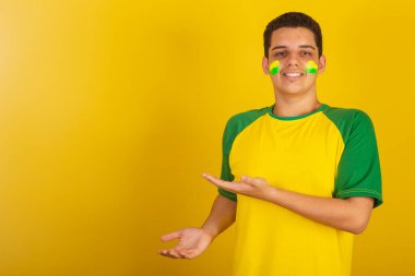 Genç Brezilyalı futbol fanatiği. Yeşil giyinmiş, bir şey sunuyor.