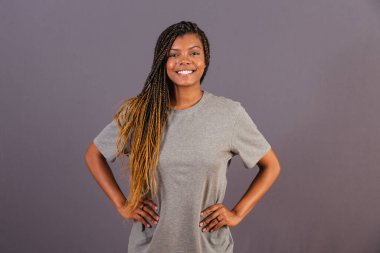 Genç bir afro Brezilyalı, elleri kalçasında, mutlu, gülümsüyor. güvenmek.