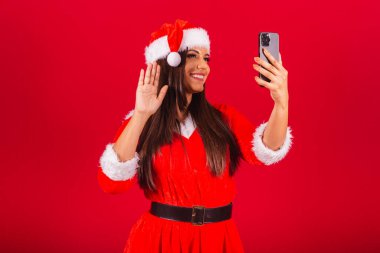 Noel kıyafetleri giymiş güzel Brezilyalı kadın, Noel Baba. Akıllı telefon video araması tutuluyor.