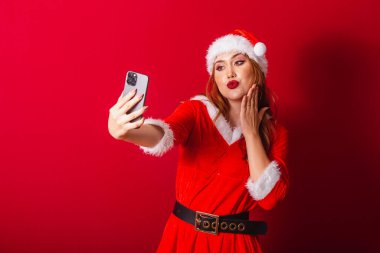Güzel Brezilyalı kızıl saçlı kadın, Noel kıyafetleri giymiş, Noel Baba. akıllı telefondan video çağrısı.