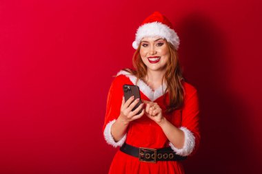 Güzel Brezilyalı kızıl saçlı kadın, Noel kıyafetleri giymiş, Noel Baba. Akıllı telefon, daktilo.