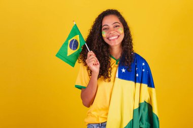 Genç siyah Brezilyalı kadın, futbol fanatiği. Bayrak sallayan, vatansever, milliyetçi.